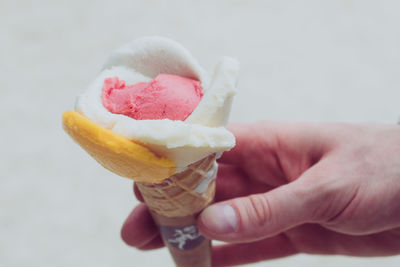 Cropped image of person holding ice cream against wall