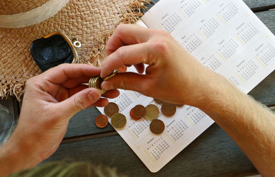 Cropped hands of man calculating money on diary