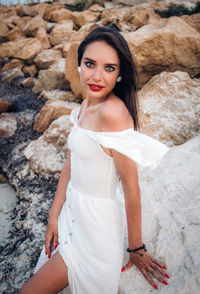 Portrait of beautiful young woman standing on rock