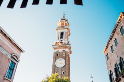 Low angle view of clock tower amidst buildings against sky