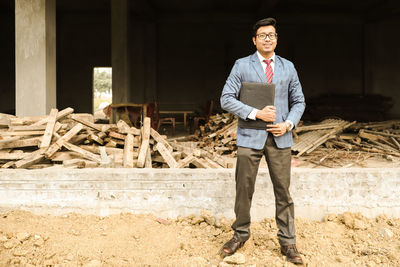 Full length portrait of young man standing on wooden logs