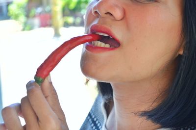 Close-up portrait of woman eating red chili