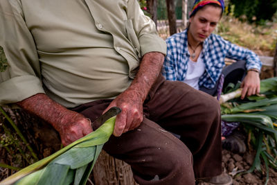 Midsection of man holding food while sitting outdoors