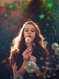 Beautiful woman blowing dandelion while standing in park