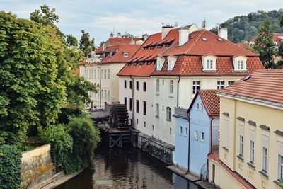 Houses by canal amidst buildings against sky