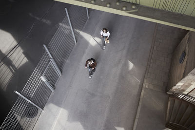 High angle view of male and female friends riding electric push scooters on street in city