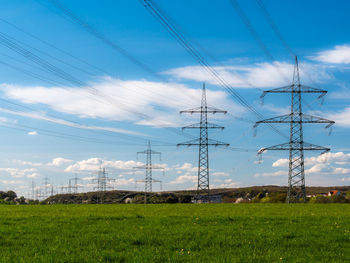 Electricity pylon on field against sky