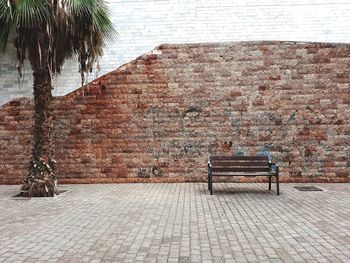 Empty bench on brick wall with graffiti