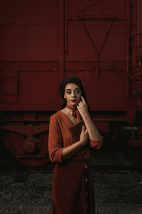 Portrait of young woman standing against red wall