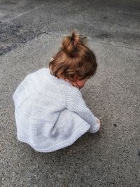 High angle view of girl crouching on road