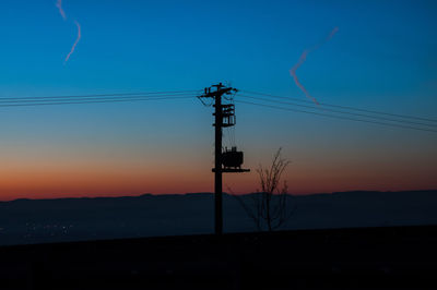 Silhouette electricity pylon against sky during sunset