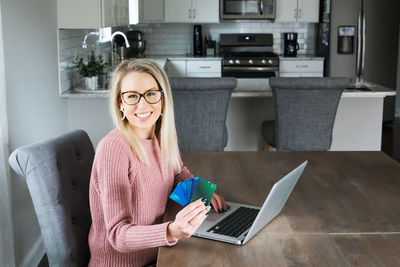 Portrait of smiling woman using laptop at home