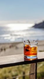 Close-up of cocktail glass on beach against sky