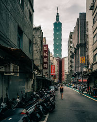 Vehicles on road amidst buildings in city against sky