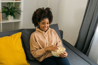 Portrait of young woman sitting on sofa at home