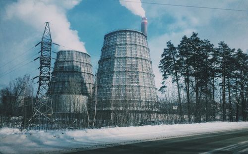 Smoke emitting from factory against sky during winter