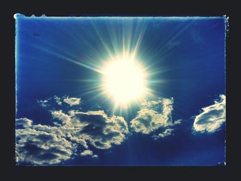 Low angle view of sun shining through clouds