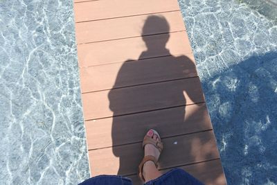 Low section of woman standing by swimming pool