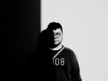 Portrait of young man standing against wall