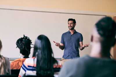 Young male teacher smiling while teaching students in language school