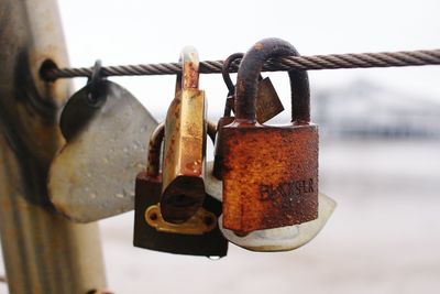 Close-up of wet padlocks hanging on bridge railing