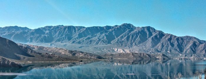 Scenic view of lake and mountains against blue sky