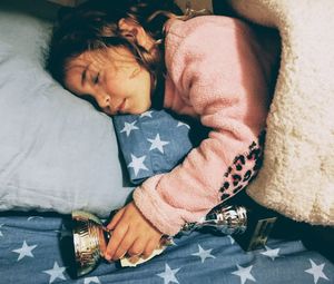 High angle view of girl sleeping with trophy on bed