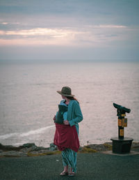 Rear view of woman walking on beach against sky