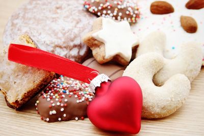 Close-up of heart shape bauble by christmas cookies on table