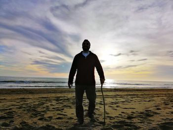 Man standing on beach against sky during sunset