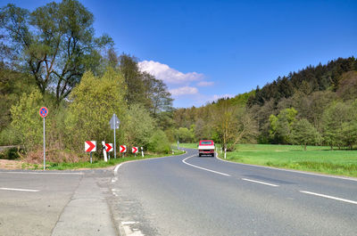 Cars on road by trees against sky