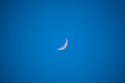 Low angle view of moon against clear blue sky