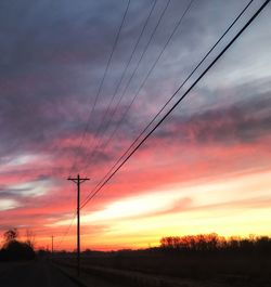 Silhouette electricity pylon against dramatic sky during sunset