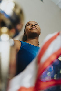 Low angle view of smiling female athlete with trophy at home