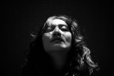 Close-up of young woman against black background