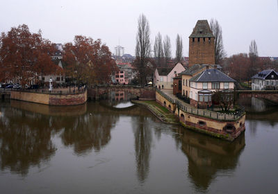Reflection of buildings and trees in river against sky