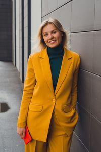 Portrait of young woman standing against wall