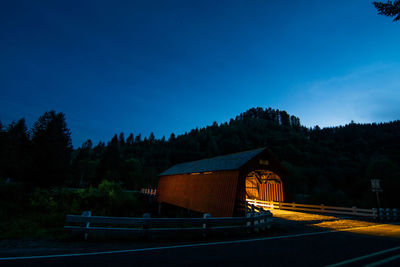 Illuminated covered walkway in forest at night