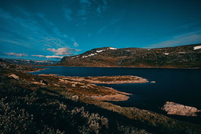 Scenic view of lake and mountains against blue sky