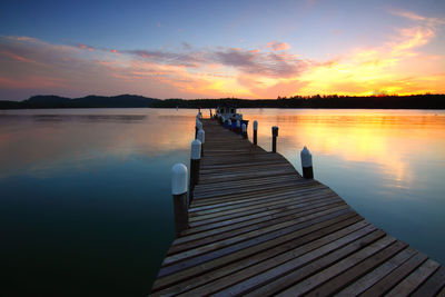 Pier over lake against sky during sunset