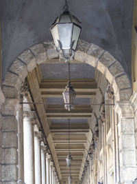 Verona, gallery with marble columns, worked wood ceiling and large lamp in the foreground