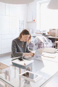 Woman using phone while sitting on table