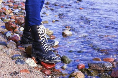 Low section of person standing on rocks at beach