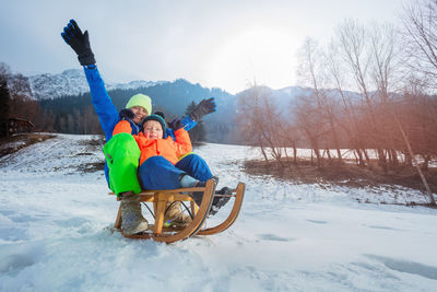 Rear view of man sitting on snow covered landscape