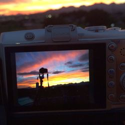 Close-up of silhouette camera against sky during sunset