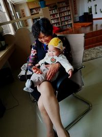 Mother and daughter sitting on chair at home