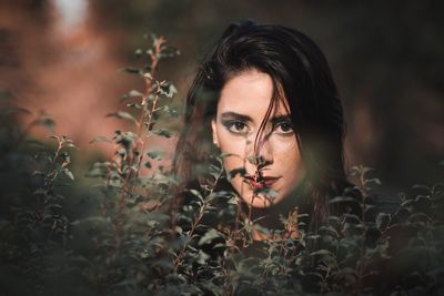 Portrait of young woman standing by plants