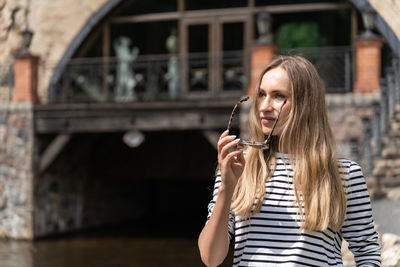 Long-haired woman takes off her sunglasses looking away