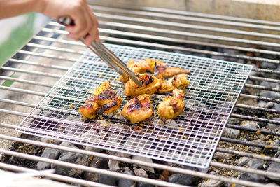 Close-up of person preparing food on barbecue grill