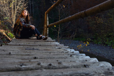 Woman sitting on wood in forest